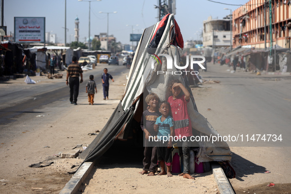 Displaced Palestinian children are posing for a picture near their tent set on a road's median at a makeshift displacement camp set up along...