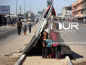 Displaced Palestinian children are posing for a picture near their tent set on a road's median at a makeshift displacement camp set up along...