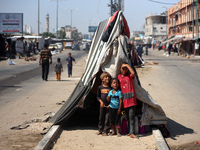 Displaced Palestinian children are posing for a picture near their tent set on a road's median at a makeshift displacement camp set up along...