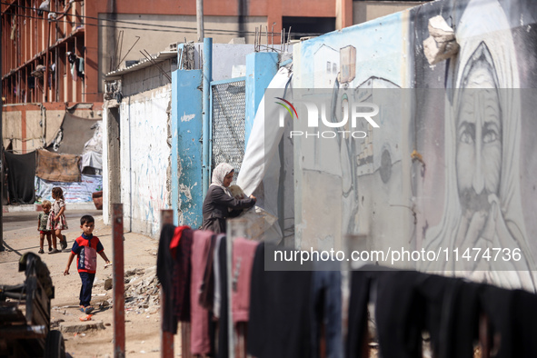 Displaced Palestinians are walking near their tents at a makeshift displacement camp set up on a roadside in Deir el-Balah in the central Ga...