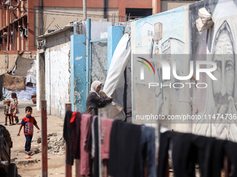 Displaced Palestinians are walking near their tents at a makeshift displacement camp set up on a roadside in Deir el-Balah in the central Ga...