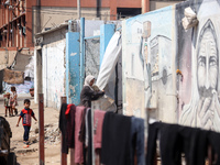 Displaced Palestinians are walking near their tents at a makeshift displacement camp set up on a roadside in Deir el-Balah in the central Ga...