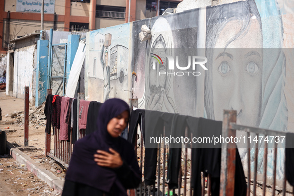 Displaced Palestinians are walking near their tents at a makeshift displacement camp set up on a roadside in Deir el-Balah in the central Ga...