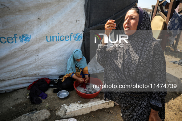 Displaced Palestinians are doing chores by their tents at a makeshift displacement camp set up on a roadside in Deir el-Balah in the central...