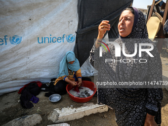 Displaced Palestinians are doing chores by their tents at a makeshift displacement camp set up on a roadside in Deir el-Balah in the central...