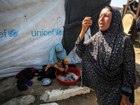 Displaced Palestinians are doing chores by their tents at a makeshift displacement camp set up on a roadside in Deir el-Balah in the central...