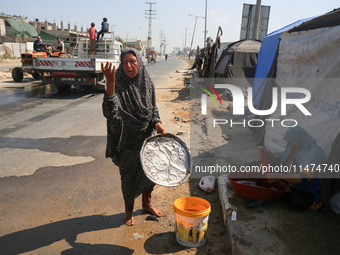 Displaced Palestinians are doing chores by their tents at a makeshift displacement camp set up on a roadside in Deir el-Balah in the central...