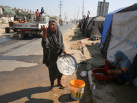 Displaced Palestinians are doing chores by their tents at a makeshift displacement camp set up on a roadside in Deir el-Balah in the central...