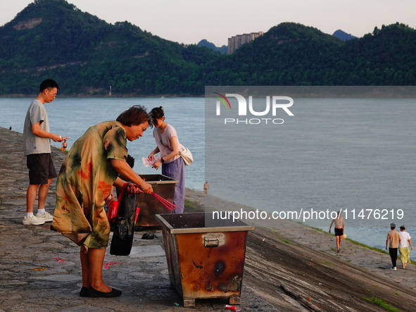 People are burning paper money to offer sacrifices to their ancestors at the Zhongyuan Festival near the banks of the Yangtze River in Yicha...