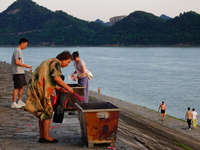 People are burning paper money to offer sacrifices to their ancestors at the Zhongyuan Festival near the banks of the Yangtze River in Yicha...