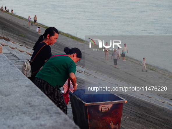 People are burning paper money to offer sacrifices to their ancestors at the Zhongyuan Festival near the banks of the Yangtze River in Yicha...