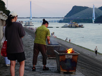 People are burning paper money to offer sacrifices to their ancestors at the Zhongyuan Festival near the banks of the Yangtze River in Yicha...