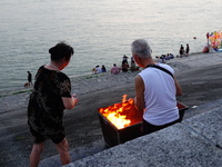 People are burning paper money to offer sacrifices to their ancestors at the Zhongyuan Festival near the banks of the Yangtze River in Yicha...