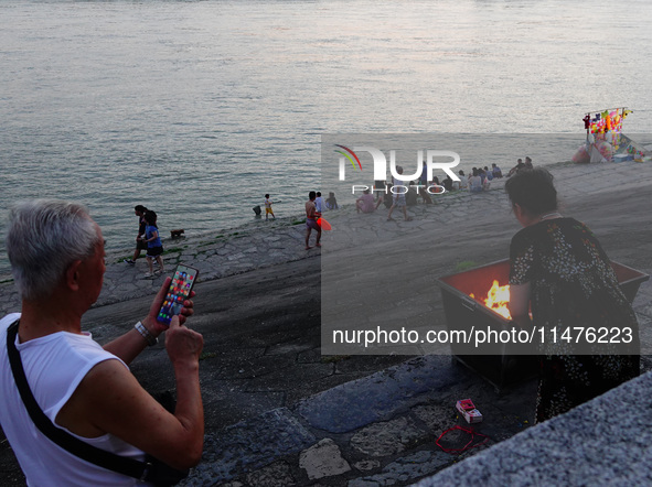 People are burning paper money to offer sacrifices to their ancestors at the Zhongyuan Festival near the banks of the Yangtze River in Yicha...