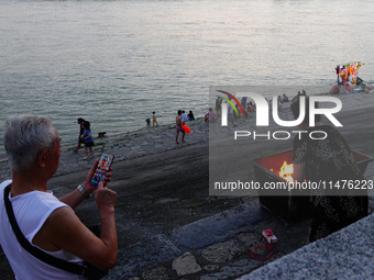 People are burning paper money to offer sacrifices to their ancestors at the Zhongyuan Festival near the banks of the Yangtze River in Yicha...