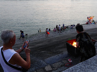 People are burning paper money to offer sacrifices to their ancestors at the Zhongyuan Festival near the banks of the Yangtze River in Yicha...