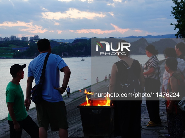 People are burning paper money to offer sacrifices to their ancestors at the Zhongyuan Festival near the banks of the Yangtze River in Yicha...