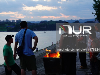 People are burning paper money to offer sacrifices to their ancestors at the Zhongyuan Festival near the banks of the Yangtze River in Yicha...