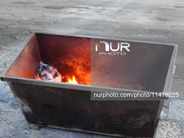 People are burning paper money to offer sacrifices to their ancestors at the Zhongyuan Festival near the banks of the Yangtze River in Yicha...