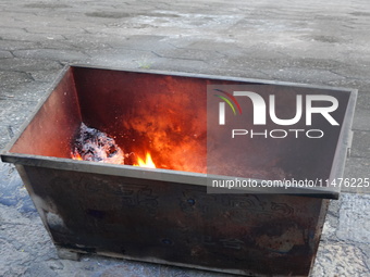 People are burning paper money to offer sacrifices to their ancestors at the Zhongyuan Festival near the banks of the Yangtze River in Yicha...