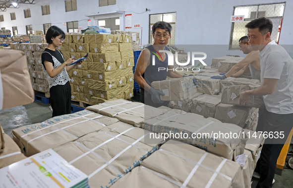 A staff member is carrying and arranging textbooks for the new semester at the textbook distribution center of New China Book Store in Zaozh...