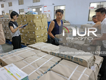 A staff member is carrying and arranging textbooks for the new semester at the textbook distribution center of New China Book Store in Zaozh...