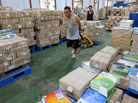 A staff member is carrying and arranging textbooks for the new semester at the textbook distribution center of New China Book Store in Zaozh...