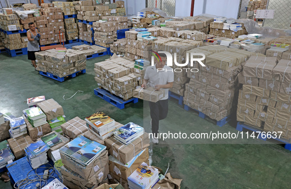 A staff member is carrying and arranging textbooks for the new semester at the textbook distribution center of New China Book Store in Zaozh...