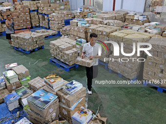 A staff member is carrying and arranging textbooks for the new semester at the textbook distribution center of New China Book Store in Zaozh...