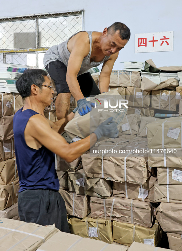 A staff member is carrying and arranging textbooks for the new semester at the textbook distribution center of New China Book Store in Zaozh...