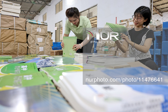 A staff member is carrying and arranging textbooks for the new semester at the textbook distribution center of New China Book Store in Zaozh...