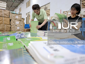 A staff member is carrying and arranging textbooks for the new semester at the textbook distribution center of New China Book Store in Zaozh...