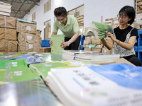 A staff member is carrying and arranging textbooks for the new semester at the textbook distribution center of New China Book Store in Zaozh...