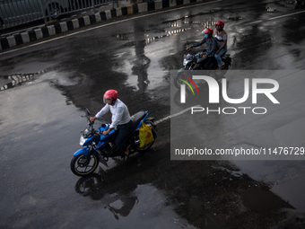 Bike riders are riding their motorcycles after rain during rush hour in Dhaka, Bangladesh, on August 13, 2024. (