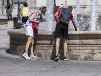 Tourist, visitors and locals are walking past Syntagma Square with the famous fountain during a heatwave in Athens with the high temperature...