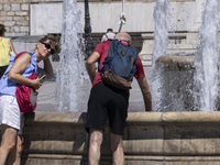 Tourist, visitors and locals are walking past Syntagma Square with the famous fountain during a heatwave in Athens with the high temperature...