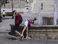 Tourist, visitors and locals are walking past Syntagma Square with the famous fountain during a heatwave in Athens with the high temperature...