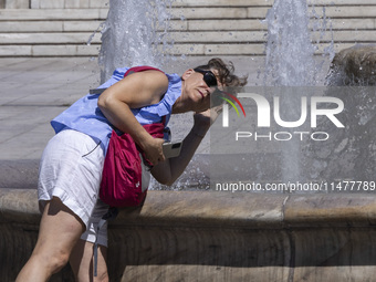 Tourist, visitors and locals are walking past Syntagma Square with the famous fountain during a heatwave in Athens with the high temperature...