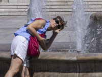 Tourist, visitors and locals are walking past Syntagma Square with the famous fountain during a heatwave in Athens with the high temperature...