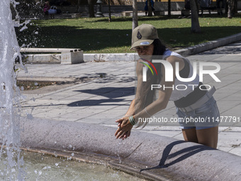 Tourist, visitors and locals are walking past Syntagma Square with the famous fountain during a heatwave in Athens with the high temperature...