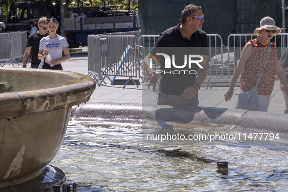 Tourist, visitors and locals are walking past Syntagma Square with the famous fountain during a heatwave in Athens with the high temperature...