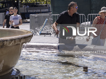 Tourist, visitors and locals are walking past Syntagma Square with the famous fountain during a heatwave in Athens with the high temperature...