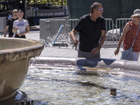 Tourist, visitors and locals are walking past Syntagma Square with the famous fountain during a heatwave in Athens with the high temperature...