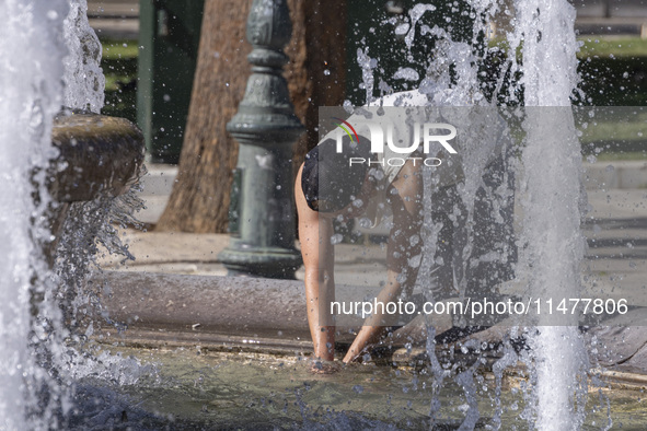 Tourist, visitors and locals are walking past Syntagma Square with the famous fountain during a heatwave in Athens with the high temperature...