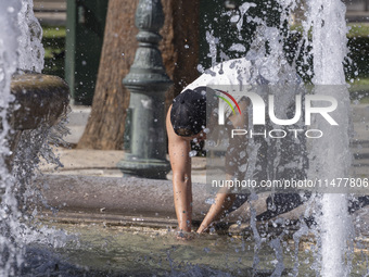 Tourist, visitors and locals are walking past Syntagma Square with the famous fountain during a heatwave in Athens with the high temperature...