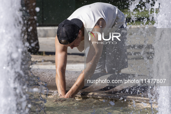 Tourist, visitors and locals are walking past Syntagma Square with the famous fountain during a heatwave in Athens with the high temperature...