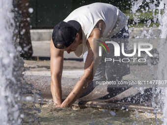 Tourist, visitors and locals are walking past Syntagma Square with the famous fountain during a heatwave in Athens with the high temperature...