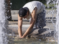 Tourist, visitors and locals are walking past Syntagma Square with the famous fountain during a heatwave in Athens with the high temperature...