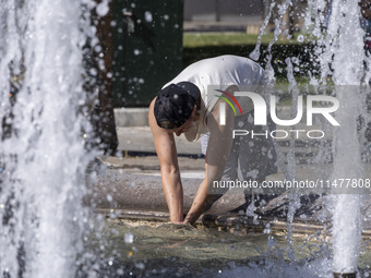 Tourist, visitors and locals are walking past Syntagma Square with the famous fountain during a heatwave in Athens with the high temperature...