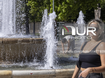 Tourist, visitors and locals are walking past Syntagma Square with the famous fountain during a heatwave in Athens with the high temperature...